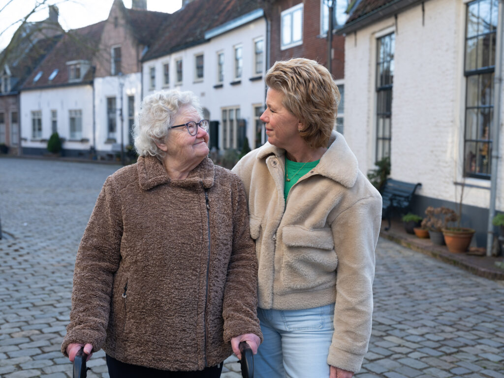 Persoonlijke begeleiding door Corina in een rustige omgeving Corina loopt samen met een oudere vrouw in een rustige omgeving, als beeld van persoonlijke aandacht en begeleiding.
